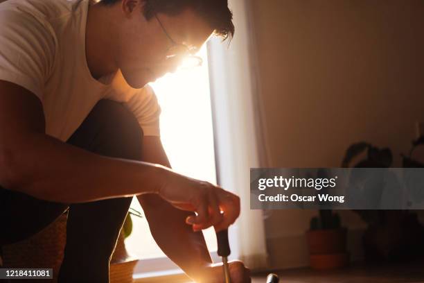 focused young man assembling furniture at home - screwdriver stock pictures, royalty-free photos & images
