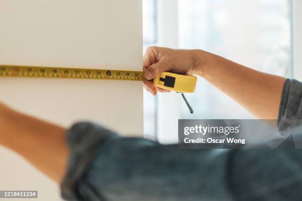 young man doing diy using measuring tape at home - tape measure stock pictures, royalty-free photos & images