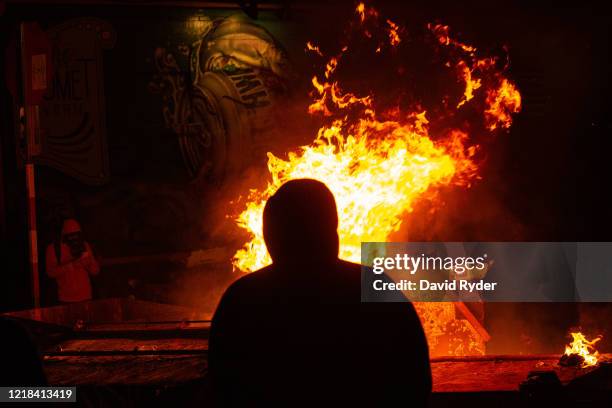 Demonstrators watch a fire burn in the street after clashing with law enforcement near the Seattle Police Departments East Precinct shortly after...