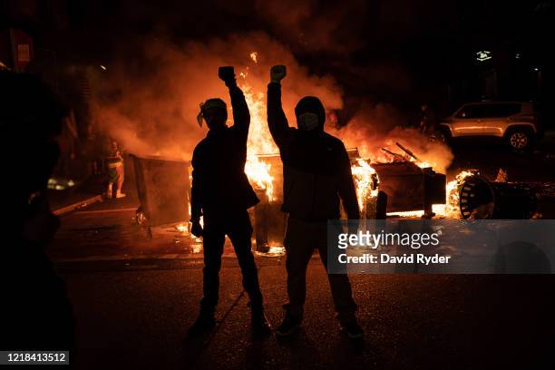 Demonstrators raise their fists as a fire burns in the street after clashes with law enforcement near the Seattle Police Departments East Precinct...