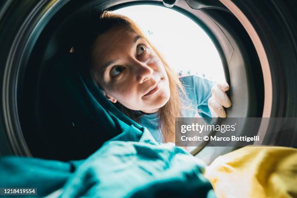 woman with gloves inspects the inside of a washing machine - sauber stock-fotos und bilder