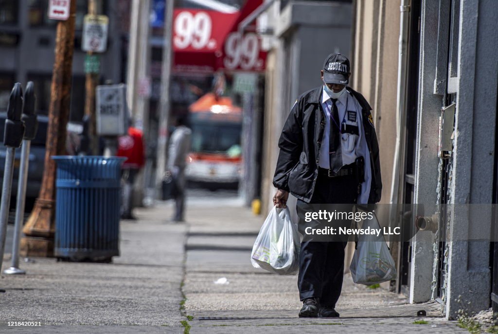 A Man Wearing A Security Guard Uniform and a Mask Walks in Hempstead, New York Carrying Groceries