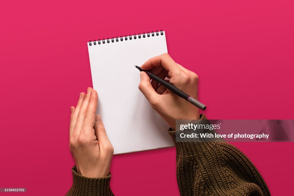Creative occupation, creativity, writing in a blank notepad on pink background, hands, goals setting background