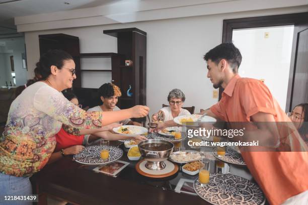 家庭在餐桌上享用午餐,配以費約達,典型的巴西黑豆燉肉 - feijoada 個照片及圖片檔