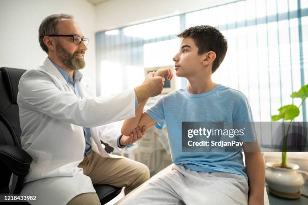 doctor checks the mobility of the boy's arm - human joint stock pictures, royalty-free photos & images