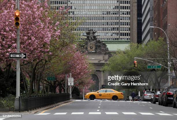 Taxi cab drives across a virtually empty Park Avenue in front of Grand Central Terminal on Easter Sunday on April 12, 2020 in New York City.