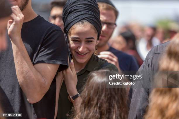 jewish woman on her phone with traditional jewish headscarf smiling in the open street of mahane yehuda, the famous market in jerusalem old city, israel - orthodox judaism stock pictures, royalty-free photos & images