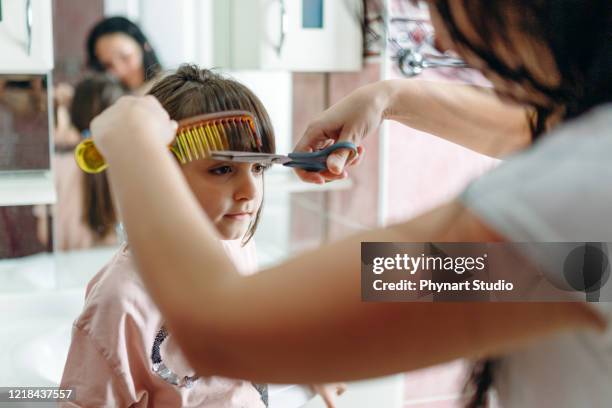 woman trying to cut her daughter's hair at home - cutting hair stock pictures, royalty-free photos & images