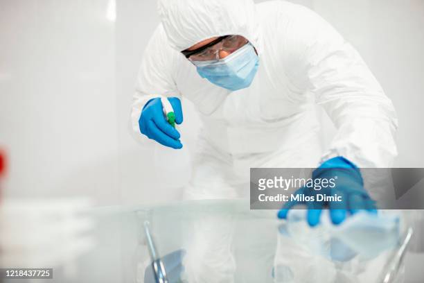 covid-19 wiping down surfaces. man with gloves and disinfectant wipe sanitizing the desk to prevent germs and bacteria infections stock photo - tidy room stock pictures, royalty-free photos & images