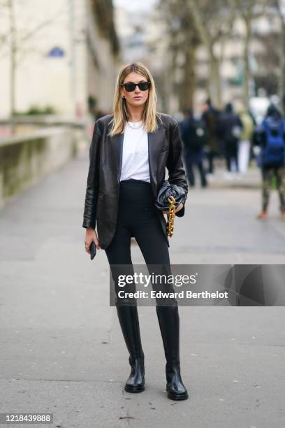Camille Charriere wears Ray-Ban sunglasses, a black leather jacket, a white t-shirt, a Bottega Veneta leather bag with a golden chain handle, black...