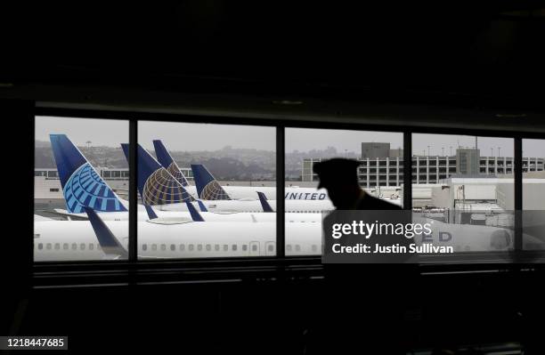 Pilot walks by United Airlines planes as they sit parked at gates at San Francisco International Airport on April 12, 2020 in San Francisco,...