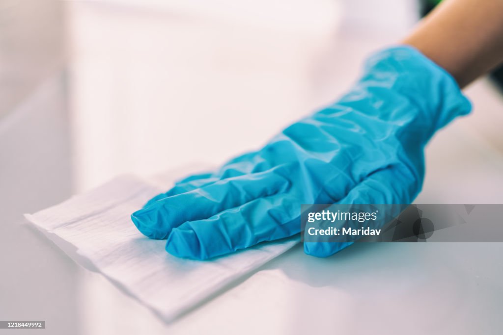 Surface disinfecting home cleaning with sanitizing antibacterial wipes protection against COVID-19 spreading wearing medical blue gloves. Sanitize surfaces prevention in hospitals and public spaces