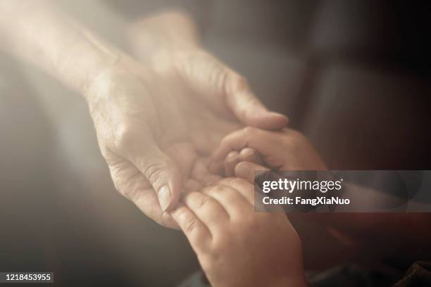 nieto sosteniendo abuela manos de cerca vista - niños orando fotografías e imágenes de stock