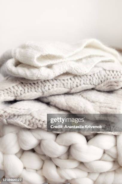 stack of cozy wool white knitted sweaters on wicker armchair. pile of merino and cashmere winter clothes. hygge style. warm concept. - lana fotografías e imágenes de stock