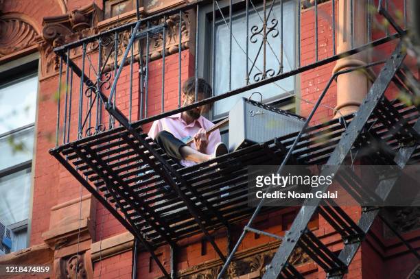 Person is seen playing the U.S. National anthem on an electric guitar from his fire escape on the East Village as people applaud to show their...
