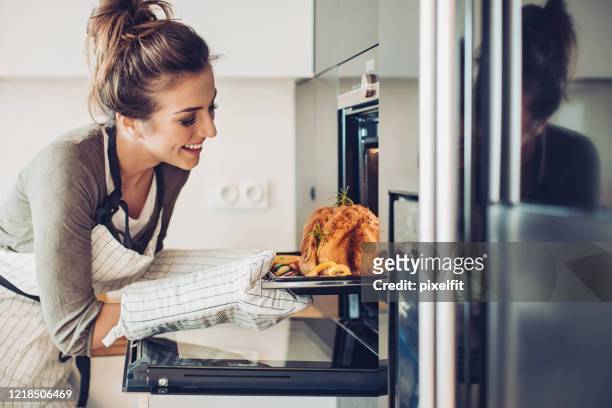 young woman baking turkey for thanksgiving - chicken roasting oven stock pictures, royalty-free photos & images
