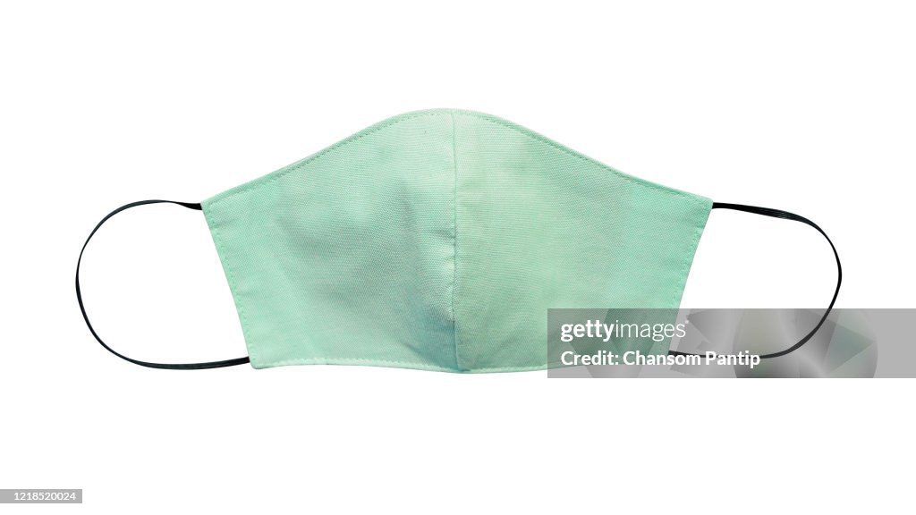 Grüne Pastell Tuch Gesichtsmaske isoliert auf weißem Hintergrund mit Clipping-Pfad. Aufgrund des Mangels an medizinischen Schutzmasken während der Coronavirus -Pandemie (COVID-19) tragen gesunde Menschen stattdessen Baumwollmasken.