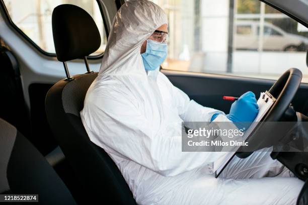 Man in protective suit in car stock photo