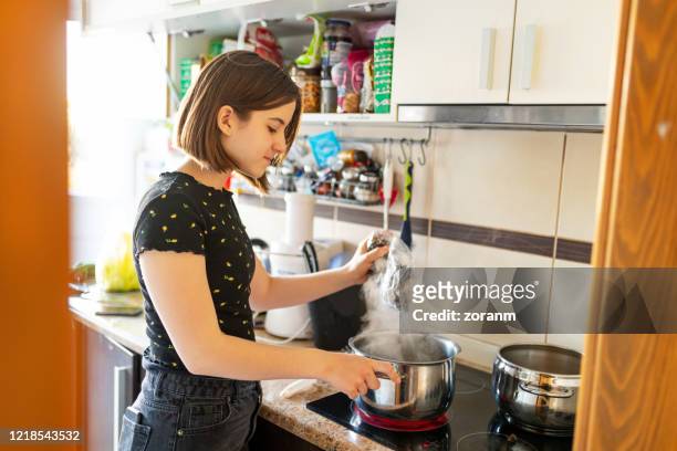tonårsflicka vid spisen matlagning pasta i potten - kokande bildbanksfoton och bilder