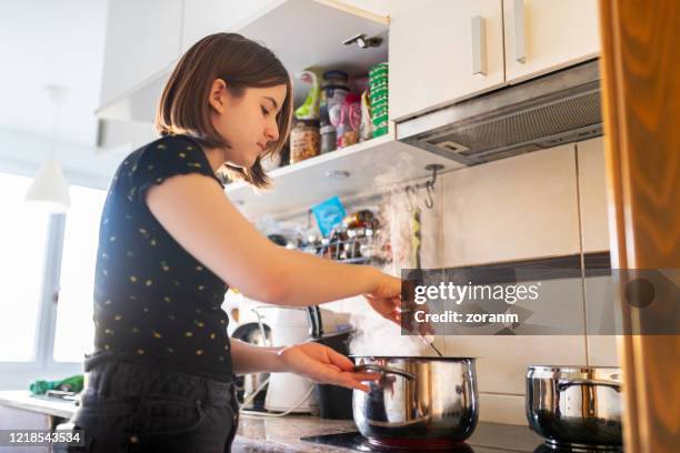 teenage girl by the stove stirring food in pot - stirring stock pictures, royalty-free photos & images