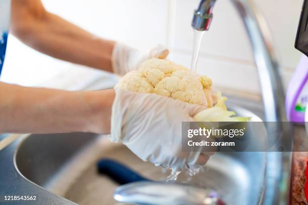 washing cauliflower under the tap by the sink - cauliflower stock pictures, royalty-free photos & images
