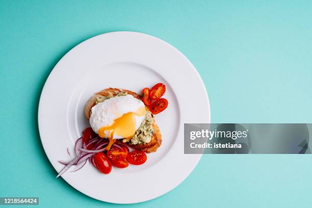 grilled bread with avocado cream and poached egg in ceramic bowl - avocado toast stockfoto's en -beelden