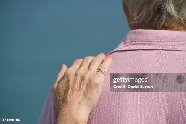 elderly lady resting her hand on her partners shoulder - man touching shoulder stockfoto's en -beelden