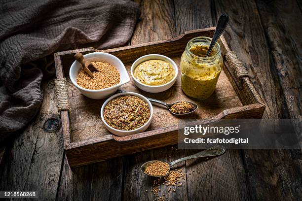 dried mustard seeds, whole grain and dijon mustard shot on rustic wooden table. - mustard stock pictures, royalty-free photos & images