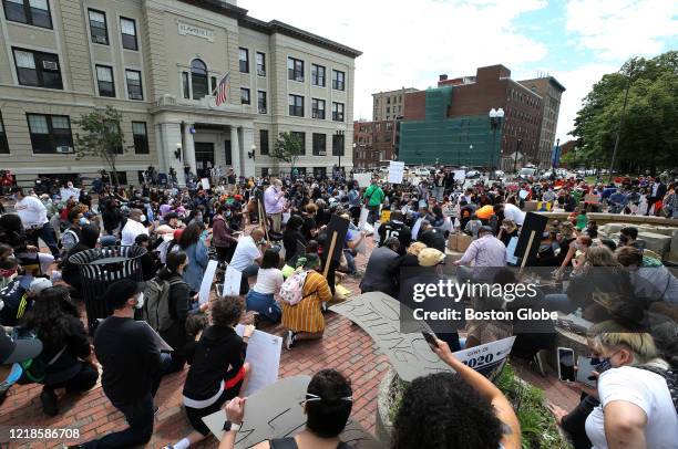 At the urging of Lawrence Mayor Daniel Rivera, with megaphone at center right, protesters kneel for 8 minutes and 46 seconds during a protest at...