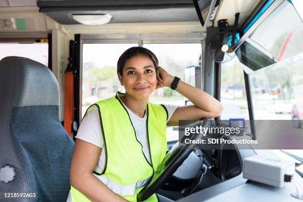 leaning on steering wheel, cheerful bus driver smiles for camera - bus driver stock pictures, royalty-free photos & images