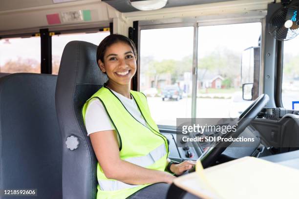 fröhlich, mittel erwachsene schulbusfahrerin lächelt für kamera - busfahrer stock-fotos und bilder