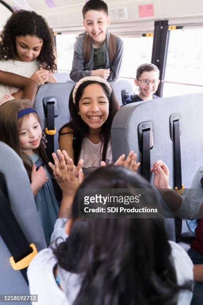 on school bus, girls play clapping game while children watch - play bus stock pictures, royalty-free photos & images