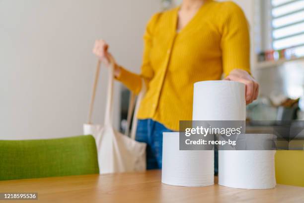 jeune femme prenant des papiers de toilette du sac à provisions à la maison - buying toilet paper photos et images de collection