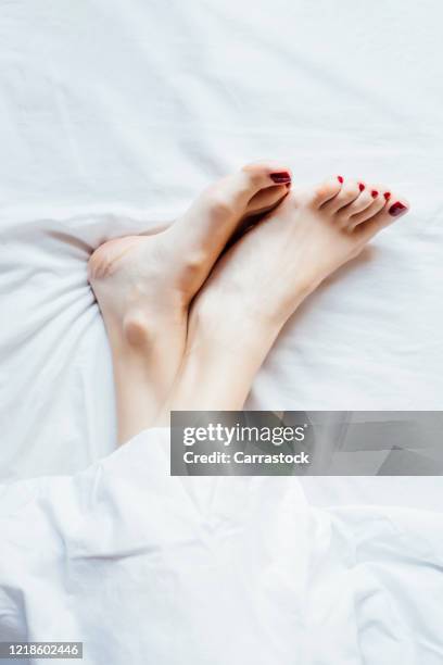 a woman's bare feet in bed. - womans bare feet fotografías e imágenes de stock