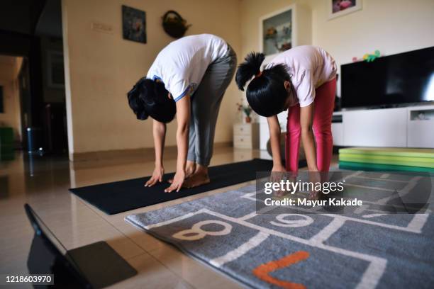 mother and daughter exercising in the living room - zehenspitzen berühren stock-fotos und bilder