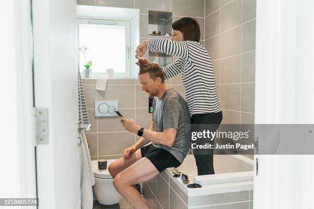women cutting partner's hair in the bathroom - bad relationship stockfoto's en -beelden
