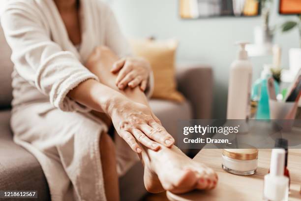 woman with beauty face mask massaging her legs and feet - his foot imagens e fotografias de stock