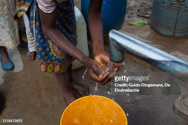 a girl washing her hands at a borehole in southern malawi. - putten stockfoto's en -beelden