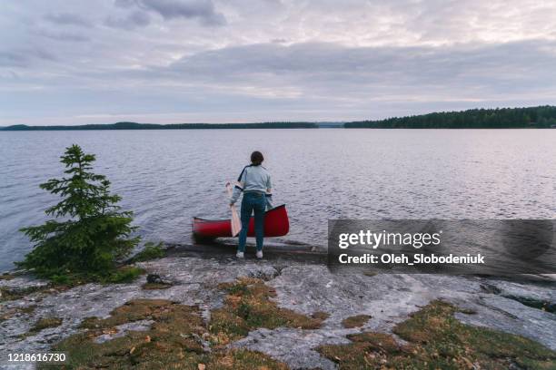 woman setting canoe on water - norwegian fjord kayaking stock pictures, royalty-free photos & images