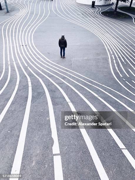 rear view of a man standing on a city street surrounded by parallel lines - street curve bildbanksfoton och bilder