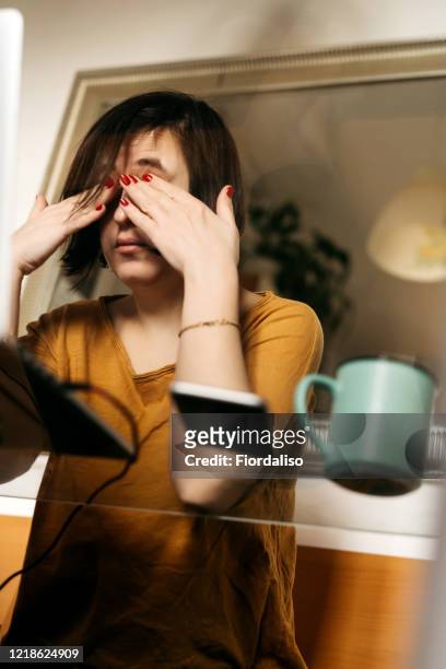 a middle-aged woman sitting in the kitchen at the glass table - zoom fatigue stock pictures, royalty-free photos & images