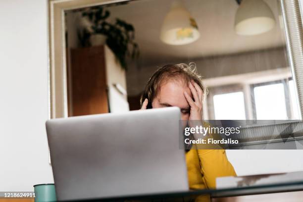 a middle-aged man sitting in the kitchen at the glass table - unemployment benefits stock pictures, royalty-free photos & images