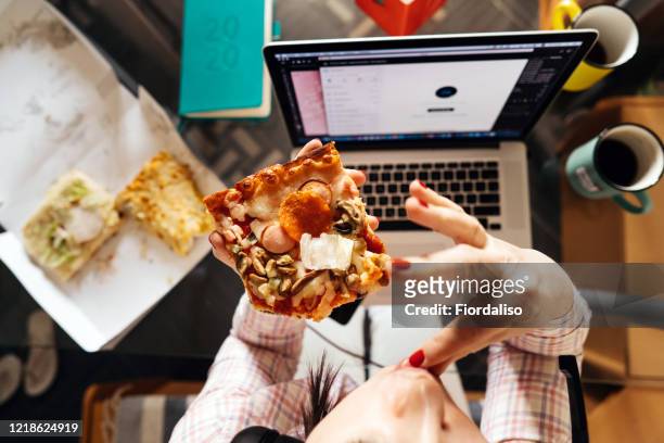 a middle-aged woman sitting in the kitchen at the glass table - junk food stock-fotos und bilder