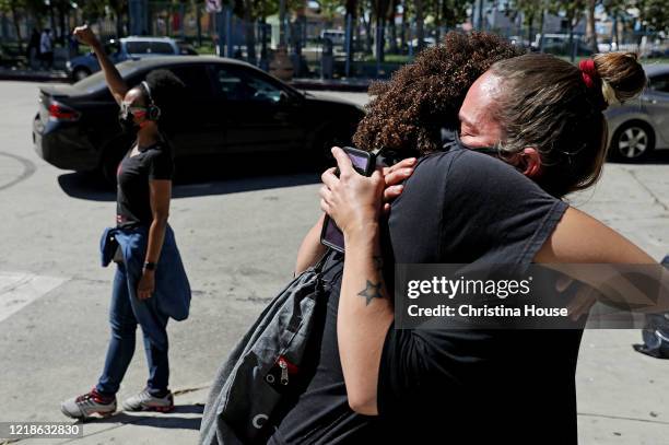 Nickey Bennett right, receives a hug from her daughter Roxi Reed after becoming emotional while watching a procession depart Leimert Park for...