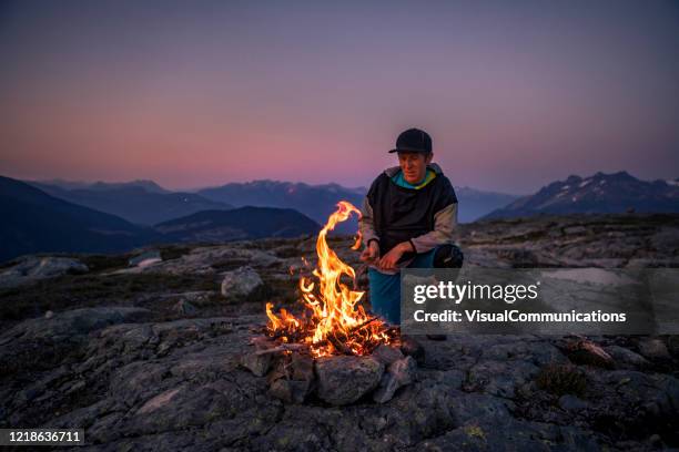 männliche camper machen lagerfeuer auf dem berg. - offenes feuer stock-fotos und bilder