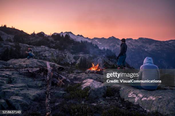 amici vicino al falò in cima alla montagna al crepuscolo. - canadian wilderness foto e immagini stock