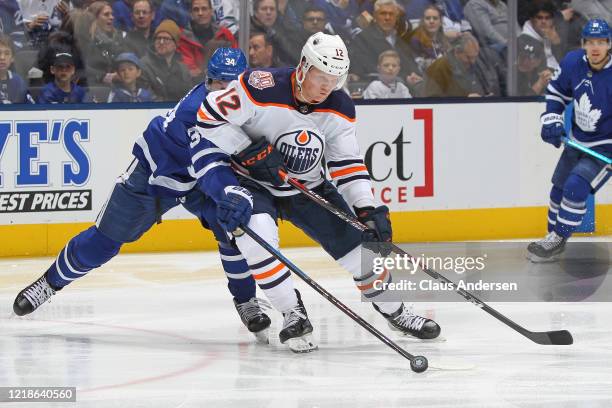 Colby Cave of the Edmonton Oilers battles for the puck against Auston Matthews of the Toronto Maple Leafs during an NHL game at Scotiabank Arena on...