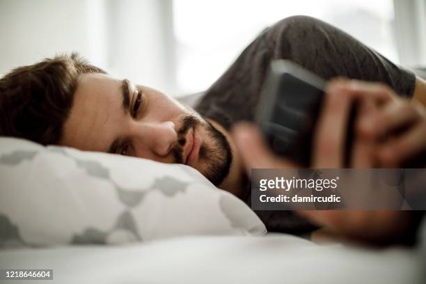 trauriger mann im bett sms-nachrichten - krankheit stock-fotos und bilder