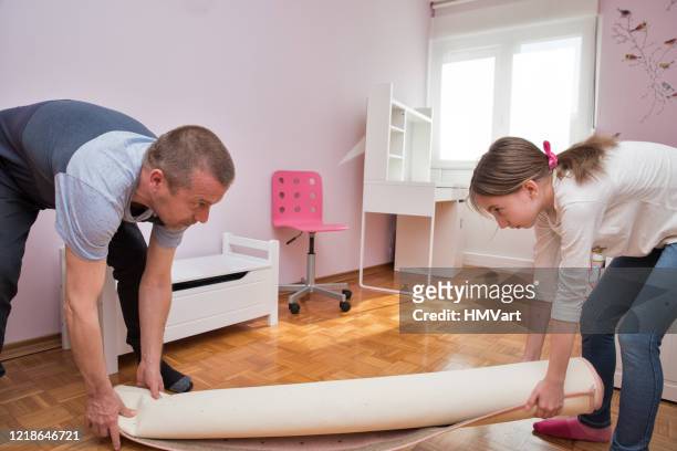 vader en dochter, tijdens de covid 19 isolatie, het verwijderen van het tapijt uit slaapkamer - renovation carpet stockfoto's en -beelden