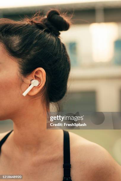 lopende accessoires: close-up van een vrouw oor met een draadloze oortelefoon - ear close up women stockfoto's en -beelden